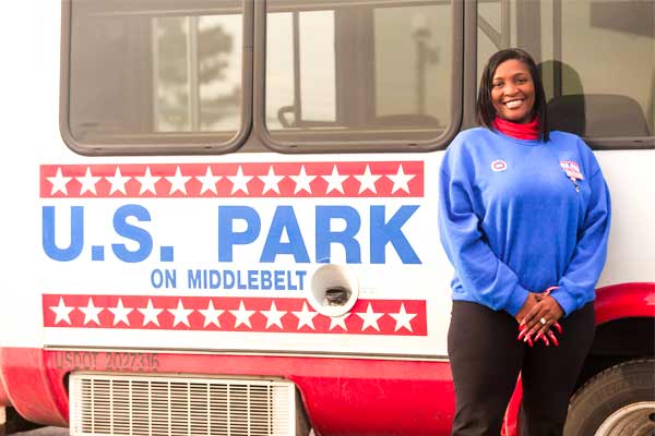 Woman standing in front of U.S. Park shuttle bus highlighting DTW parking services near Detroit Metro Airport